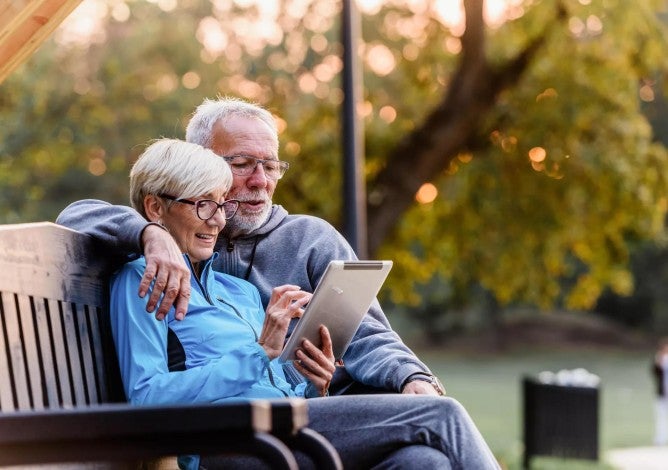 Older couple sitting on park bench discussing retirement benefits through Social Security.