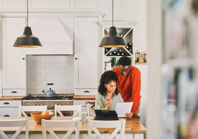 Young couple in their kitchen looking over documents as part of their financial planning.