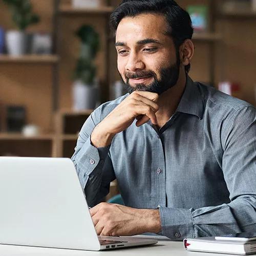 Bearded Indian business man watching online webinar on laptop computer. Bearded Indian business man watching online webinar on laptop computer.
