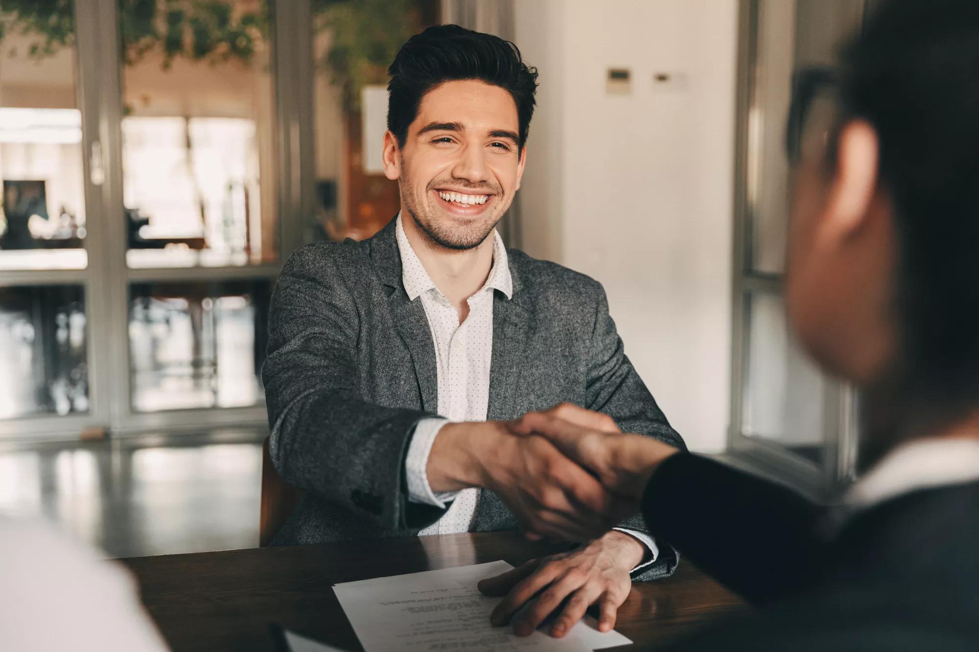 Young man shaking hands across a desk. Young man shaking hands across a desk.