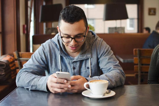 Hombre joven usando su teléfono para informarse sobre cuentas de inversión y términos de productos.