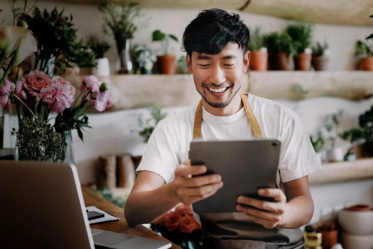 A person in a floral shop reviewing their savings online