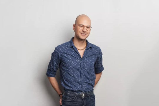 Tanner Mote smiling, standing against a white wall