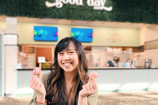 Anna Lam poses with colorful macarons in front of her bakery Good Day DSM.