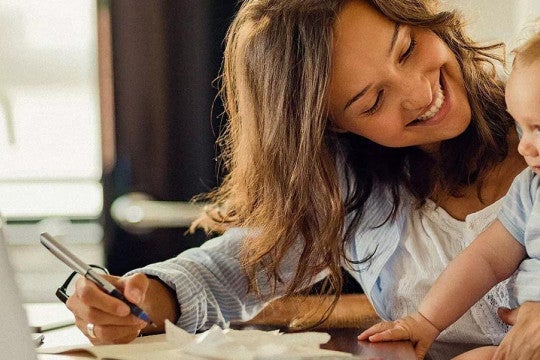 Una mujer creando un presupuesto con un bebé en brazos