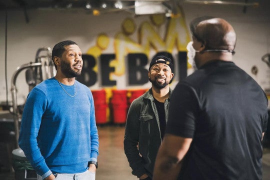 Business owners smiling while talking to their employee working in a roastery. 