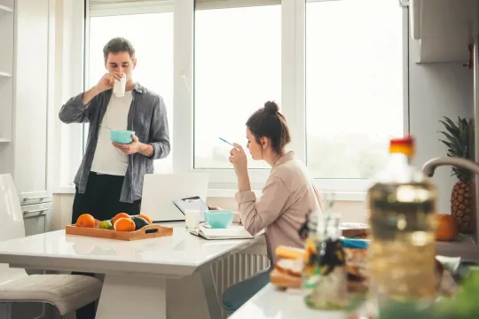 Young male and female couple eating breakfast at home while going over finances.