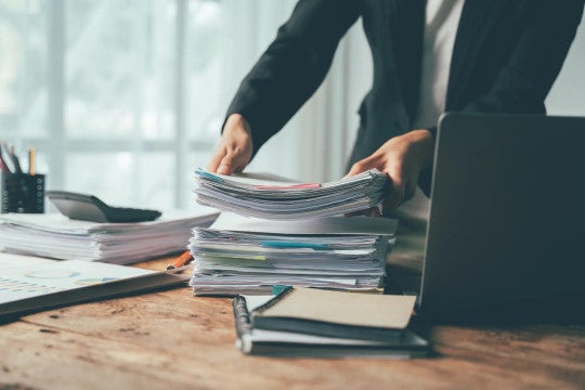 A person putting a stack of papers on a desk