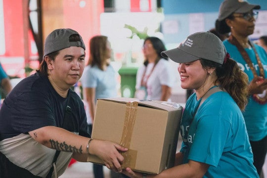 Principal employees work together to carry a box at the World Central Kitchen volunteer event.