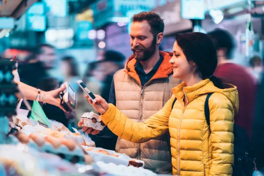 Young couple buying eggs on the street market using tap to pay.