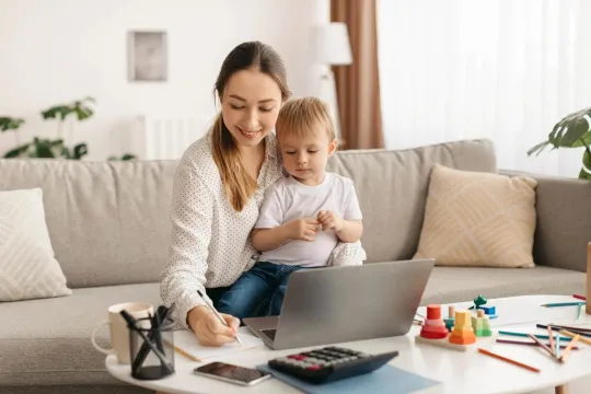 Woman working on budget and goals with toddler sitting on her lap.