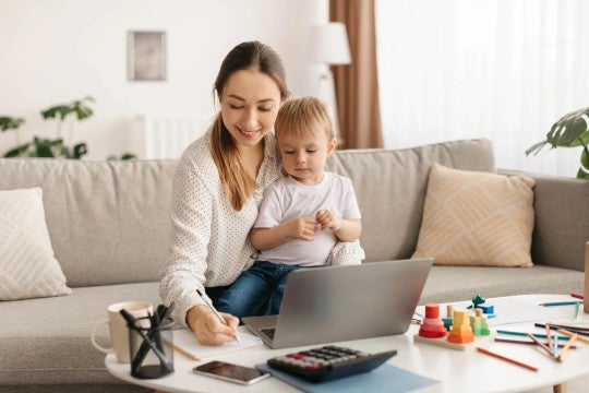 Woman working on budget and goals with toddler sitting on her lap.
