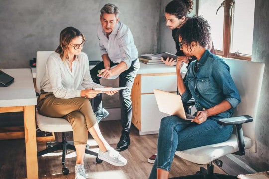 Business owner with three employees gathered together to talk
