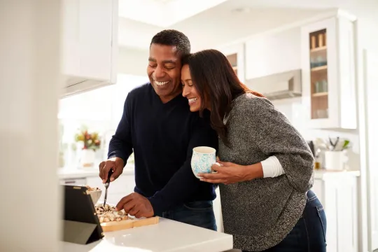 Couple reviewing retirement plan at computer, woman seated at desk.