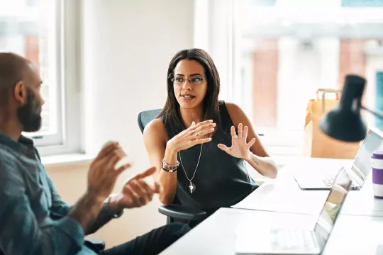 A woman and man in an office setting having a discussion.