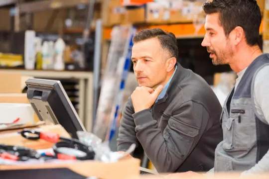 Two employees looking at a computer screen together in a work setting.