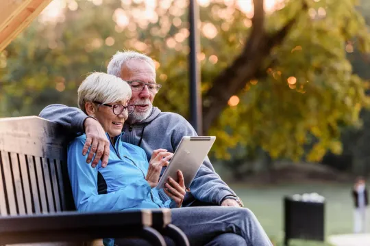 Older couple sitting on park bench discussing retirement benefits through Social Security.