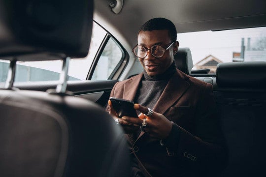 Man in suit looking at his phone to check personal information.