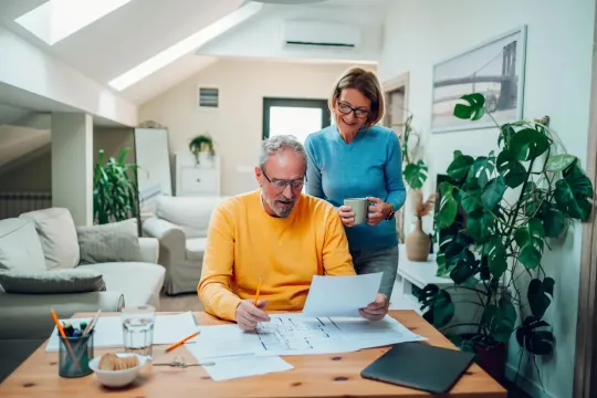 Couple in a home office reviewing financial paperwork