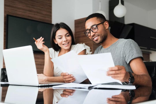Young man and woman working together at a table to create a retirement plan.