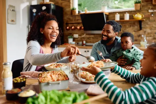 Familiy with parents and two children gathered around a table eating a meal.
