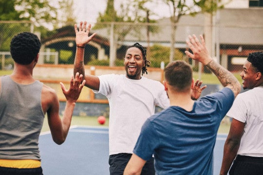 A group of athletic men high-fiving about their strong game performance—a comparative image of defined benefit (DB) plan sponsor