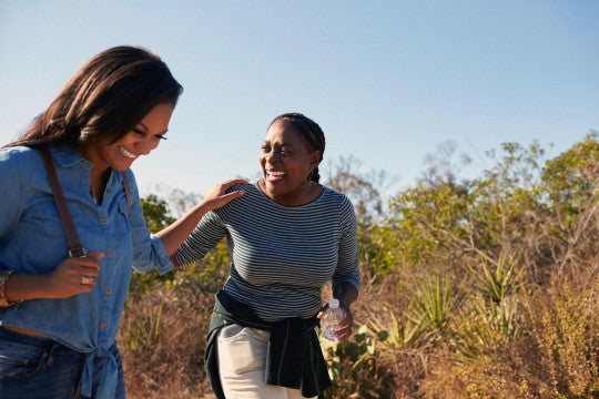 Mother and adult daughter hiking outdoors in countryside.