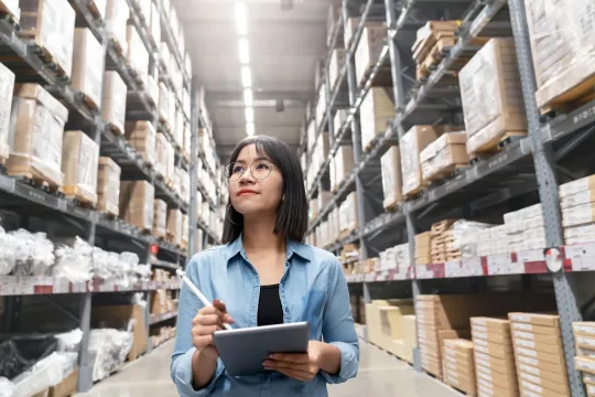A woman taking inventory in a large aisle of supplies and products.