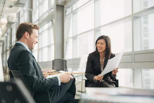 Two business people smiling as they review their defined benefits strategy