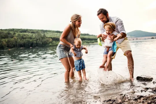 Dos padres y dos niños jugando en el agua.