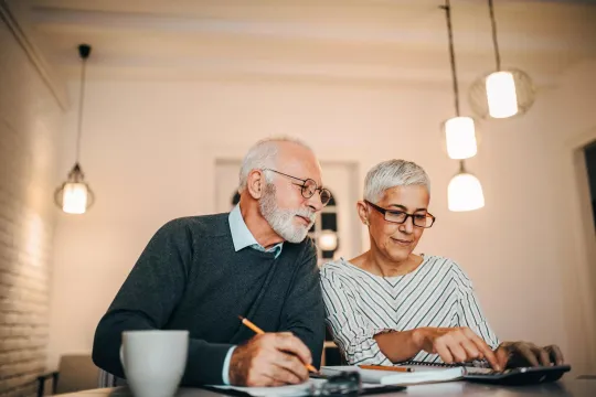 Man and woman reviewing finances with calculator and notebook.