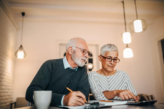 Man and woman reviewing finances with calculator and notebook.
