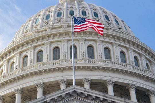 The U.S. flag flying in front of the U.S. Capitol.