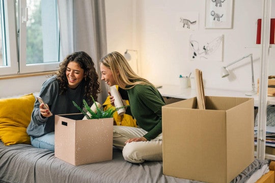 Two young adult women moving into dorm room