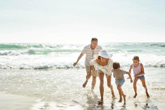 Man, woman, and two children playing in the ocean.