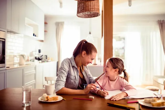 Mom and daughter at kitchen table reviewing homework