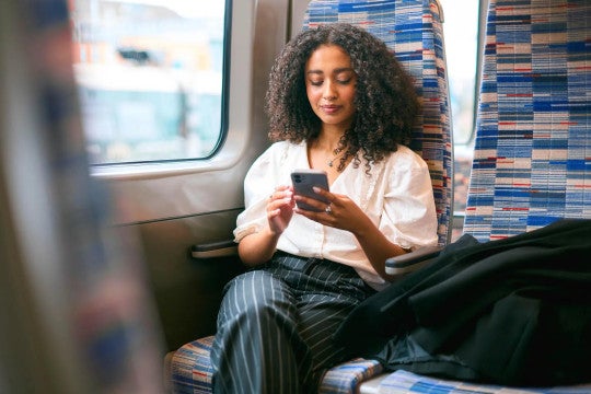 A woman looking at her phone in a seat while travelling.