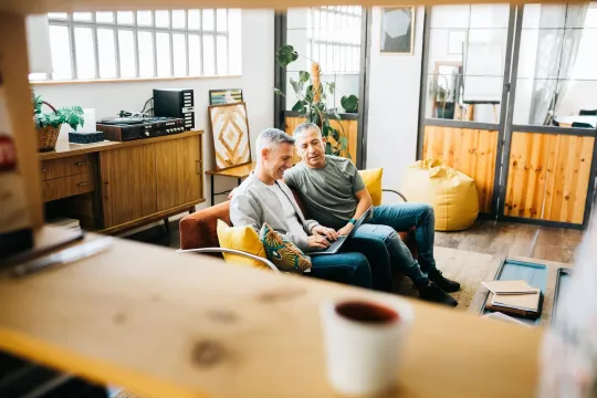 Two men looking at a laptop in a relaxed environment.