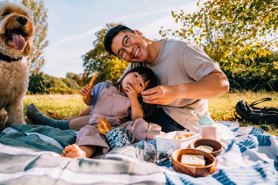 Father and daughter outside sitting on blanket having a picnic