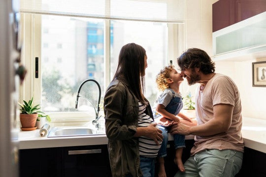 A young family sharing a tender moment in their kitchen.