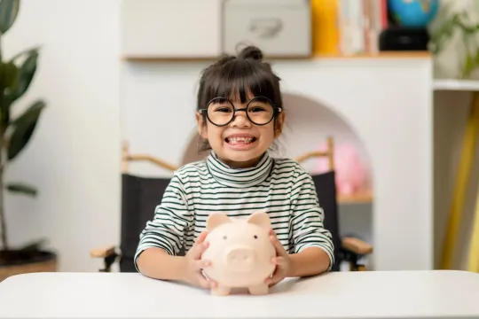 A young girl smiling with her piggy bank.