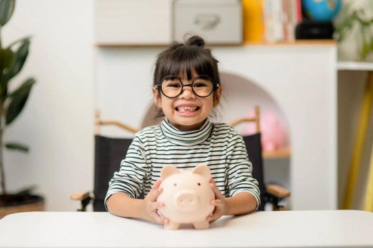 A young girl smiling with her piggy bank.