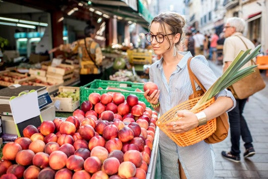 Young woman choosing fresh fruit at a farmers market