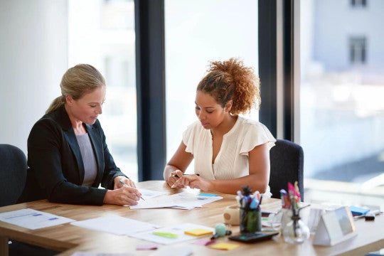 Two women sitting at a desk reviewing financial information