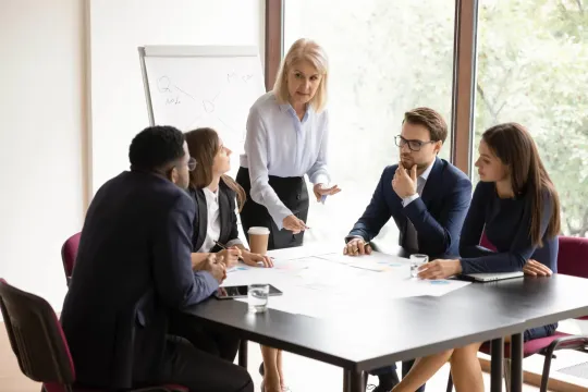 Concentrated female leader heading a diverse group of business people cooperating together