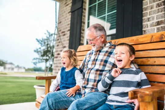 Grandfather sitting on porch swing with two grandchildren