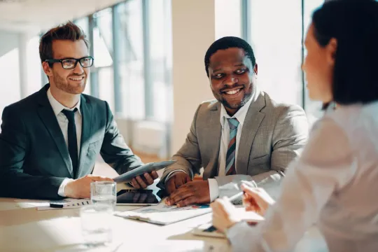 Three people talking in a meeting.