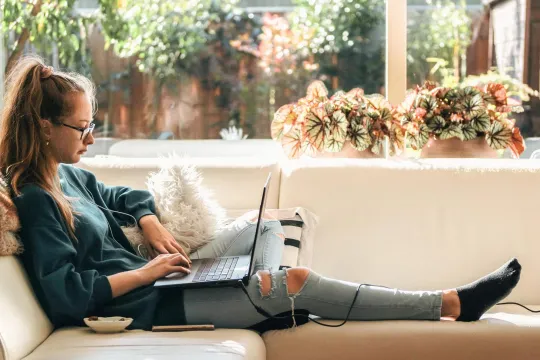 Person working on a laptop on a couch.