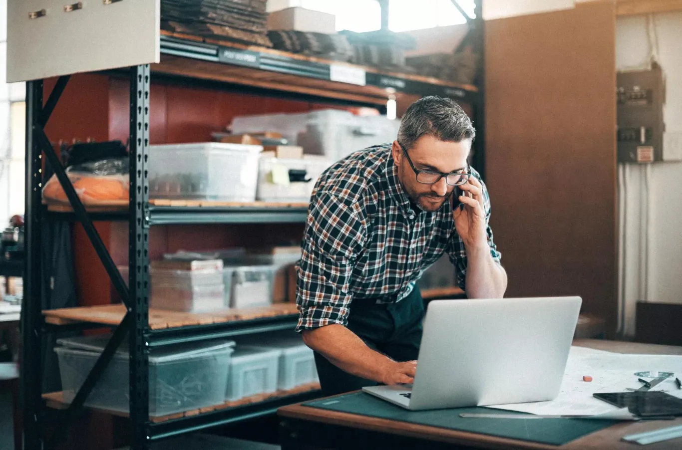 A man on the phone looking at his computer.