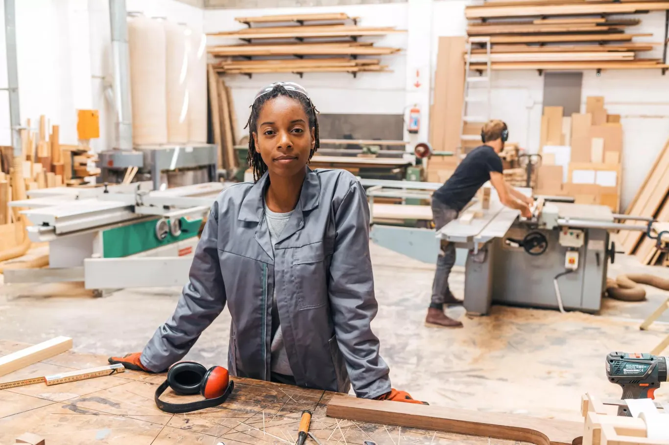 Woman standing behind a table in woodcutting area.